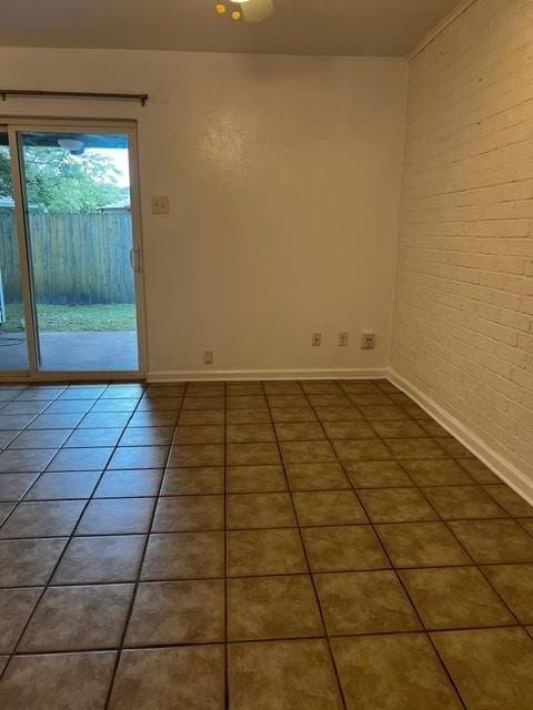 tiled empty room with brick wall and baseboards