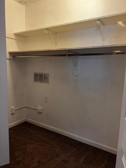 laundry area with dark carpet, visible vents, and baseboards