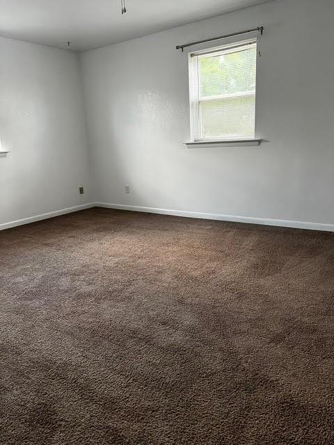 empty room with dark colored carpet and baseboards