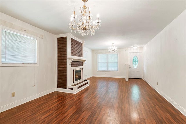 2751 Washington Ave, Slidell, LA 70458 - unfurnished living room with a chandelier, dark wood-style flooring, baseboards, and a brick fireplace