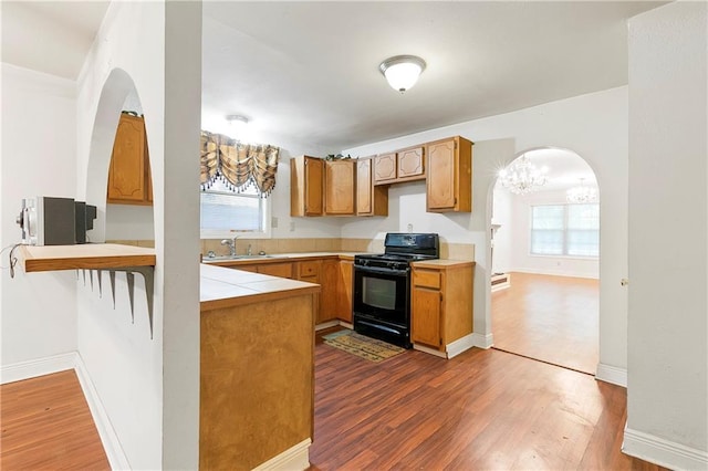 2751 Washington Ave, Slidell, LA 70458 - kitchen with black range with gas cooktop, a peninsula, arched walkways, and dark wood-style floors