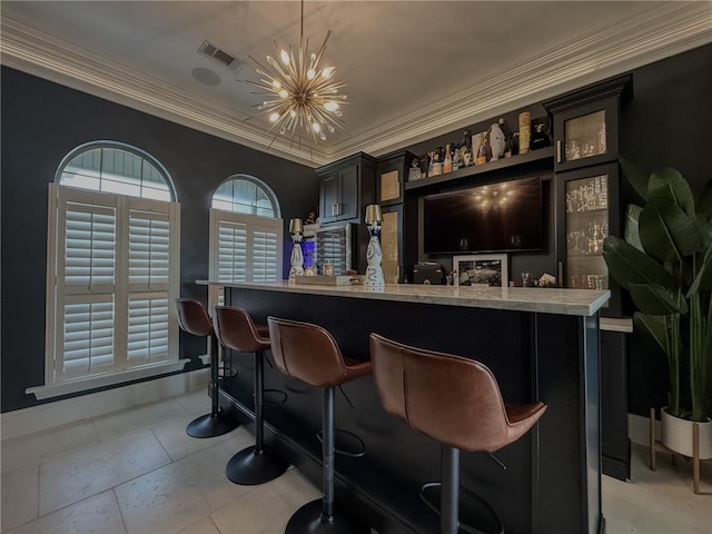bar featuring an inviting chandelier, baseboards, visible vents, a bar, and crown molding
