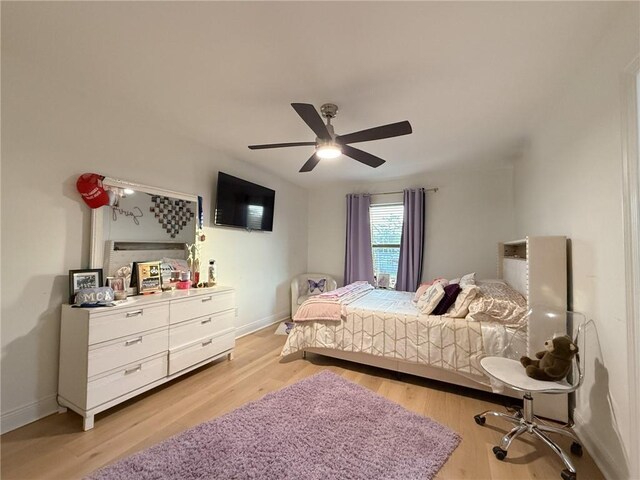 bedroom with a ceiling fan, light wood-style flooring, and baseboards