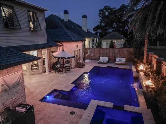 view of pool with a pool with connected hot tub, an outdoor living space with a fire pit, a fenced backyard, and a patio area