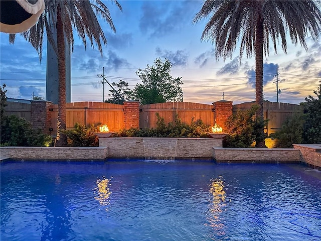 pool at dusk featuring a fenced in pool and a fenced backyard