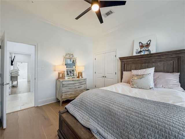bedroom featuring light wood-type flooring, baseboards, visible vents, a ceiling fan, and crown molding