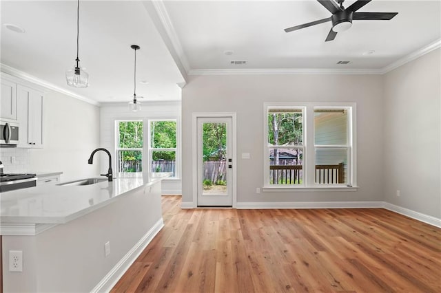 kitchen featuring stainless steel microwave, plenty of natural light, range, a sink, and baseboards