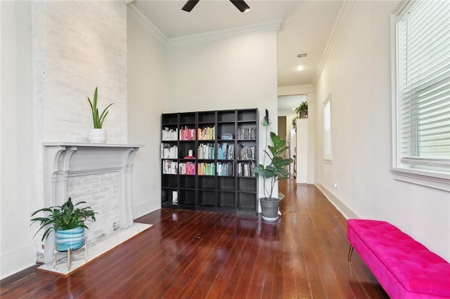 interior space with a fireplace with flush hearth, ceiling fan, ornamental molding, and wood-type flooring