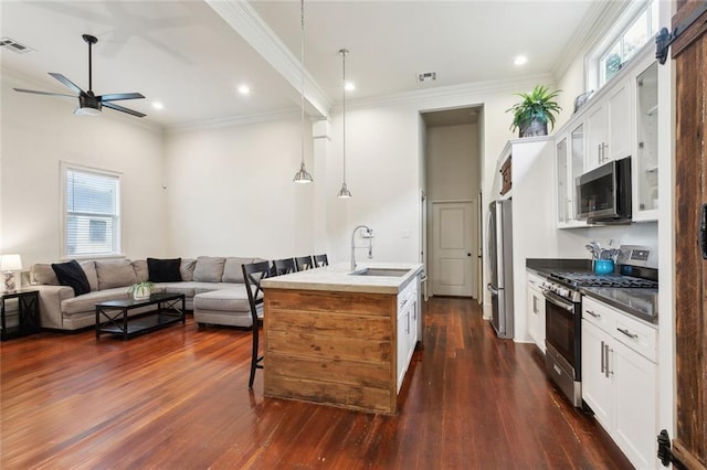 kitchen featuring open floor plan, appliances with stainless steel finishes, a kitchen bar, and a sink