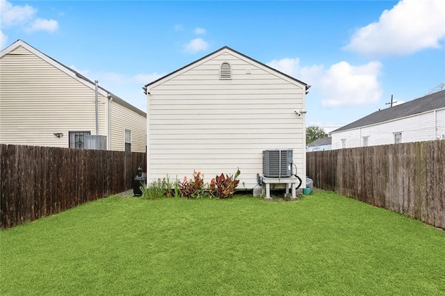 back of house featuring central AC, a yard, and a fenced backyard