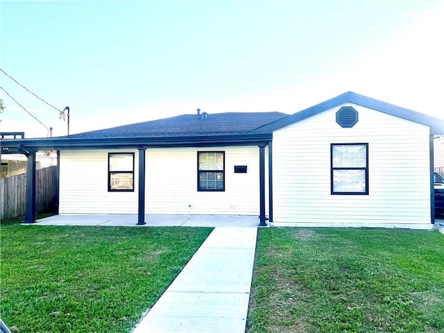 ranch-style home with a patio, a shingled roof, fence, and a front yard