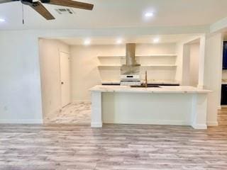 kitchen with ceiling fan, a sink, island range hood, wood finished floors, and visible vents