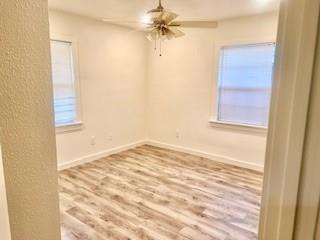unfurnished room with baseboards, a ceiling fan, and wood finished floors