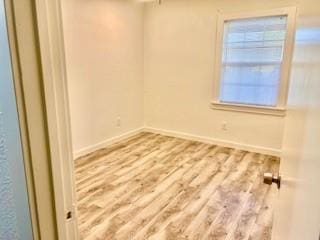 empty room with baseboards and wood finished floors