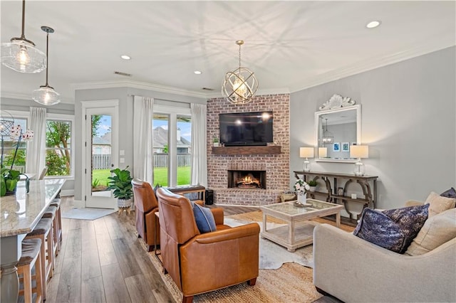 living area featuring hardwood / wood-style floors, recessed lighting, crown molding, and a brick fireplace
