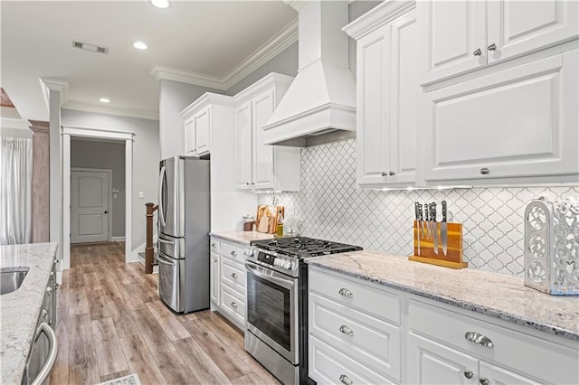 kitchen featuring white cabinets, custom range hood, stainless steel appliances, recessed lighting, and ornamental molding