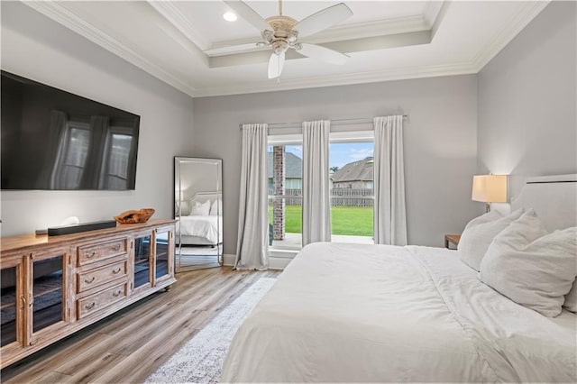bedroom featuring recessed lighting, wood finished floors, crown molding, and a tray ceiling