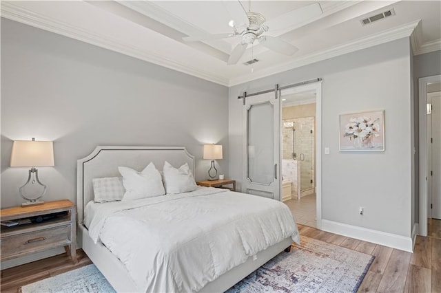 bedroom with a barn door, visible vents, ornamental molding, and wood finished floors