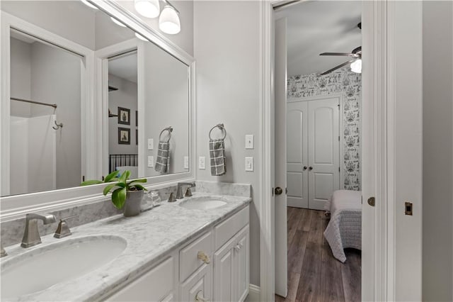 bathroom with double vanity, wood finished floors, ceiling fan, and a sink