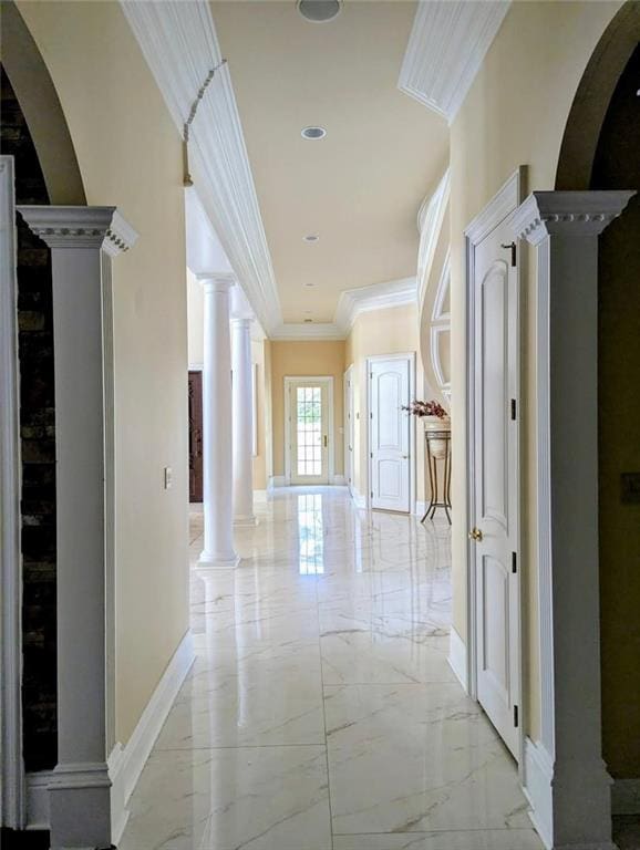 corridor featuring decorative columns, marble finish floor, baseboards, ornamental molding, and arched walkways