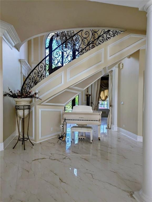 interior space with ornate columns, baseboards, marble finish floor, and stairs