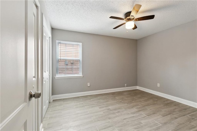 spare room featuring a textured ceiling, a ceiling fan, light wood-style flooring, and baseboards