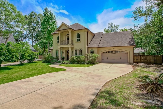 view of front of property featuring a front yard, a garage, fence, a balcony, and stucco siding