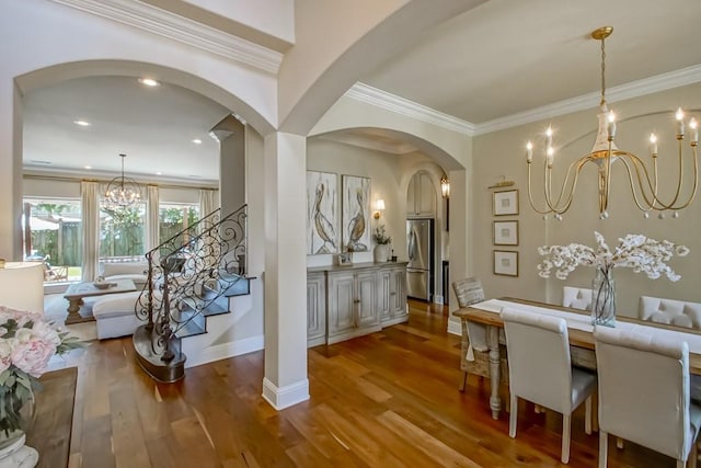 dining room featuring arched walkways, an inviting chandelier, wood finished floors, and stairway