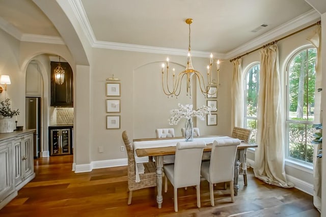 dining area with arched walkways, a chandelier, plenty of natural light, and wine cooler