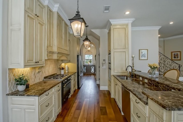 kitchen featuring visible vents, a peninsula, dark wood-type flooring, a sink, and appliances with stainless steel finishes