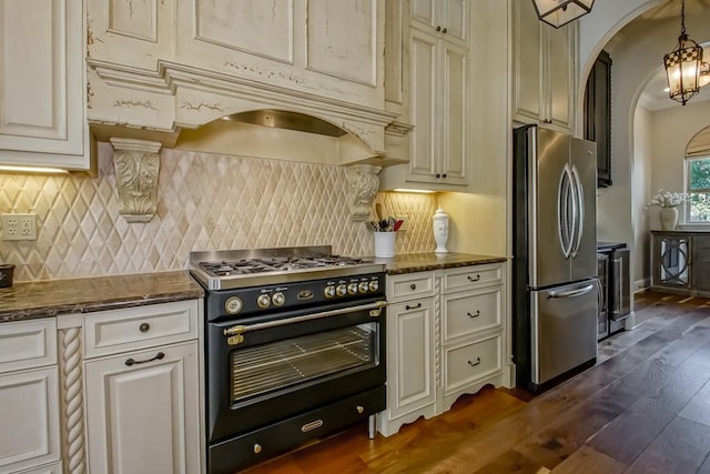 kitchen featuring decorative backsplash, dark wood-style flooring, double oven range, arched walkways, and freestanding refrigerator