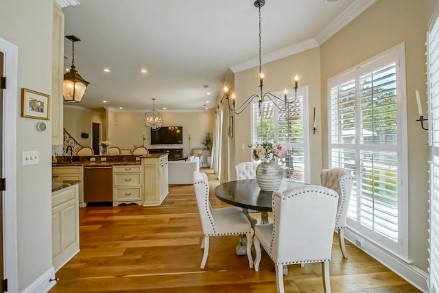 dining area featuring an inviting chandelier, ornamental molding, recessed lighting, and light wood-style flooring