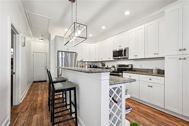 3301 Loyola Ave, New Orleans, LA 70115 - kitchen featuring white cabinets, a breakfast bar area, an island with sink, stainless steel appliances, and dark wood-style floors
