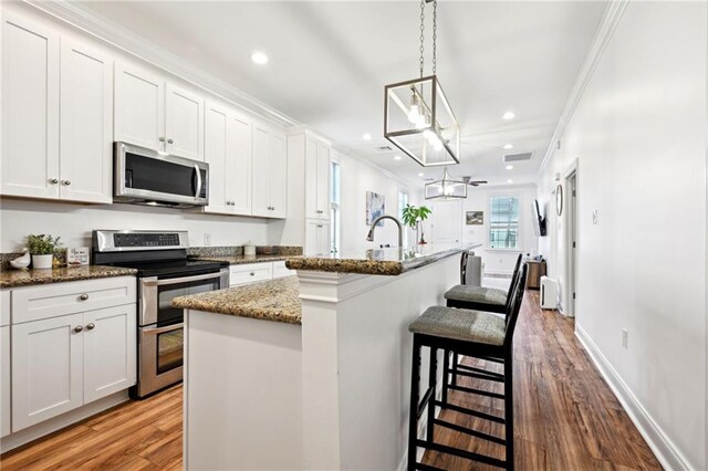 3301 Loyola Ave, New Orleans, LA 70115 - kitchen featuring white cabinets, dark stone countertops, stainless steel appliances, wood finished floors, and a center island with sink