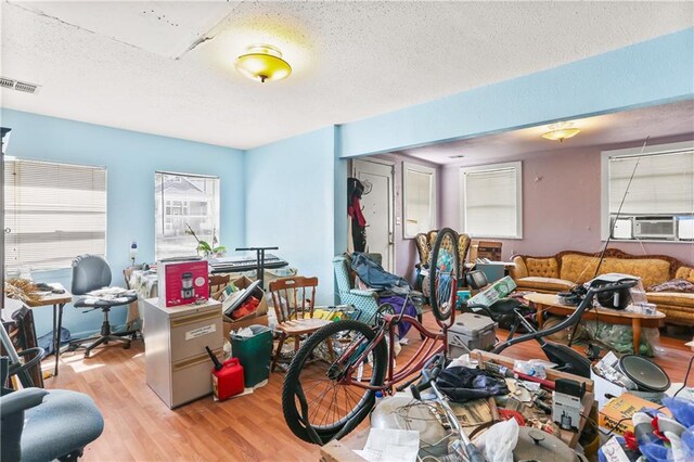 1717 Foucher St, New Orleans, LA 70115 - miscellaneous room featuring light wood-style floors, a textured ceiling, cooling unit, and visible vents