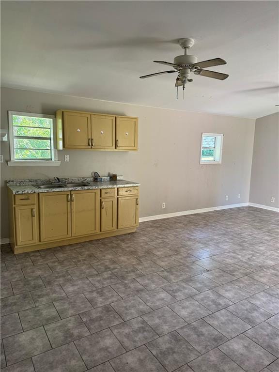 kitchen featuring a sink, baseboards, plenty of natural light, and a ceiling fan
