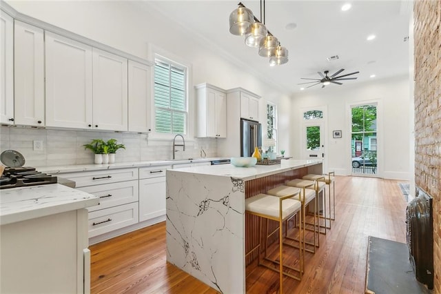 kitchen with high end refrigerator, a sink, a ceiling fan, and light wood-style flooring