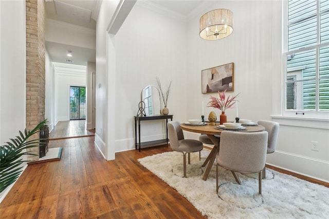 dining room featuring baseboards, a high ceiling, ornamental molding, and hardwood / wood-style floors