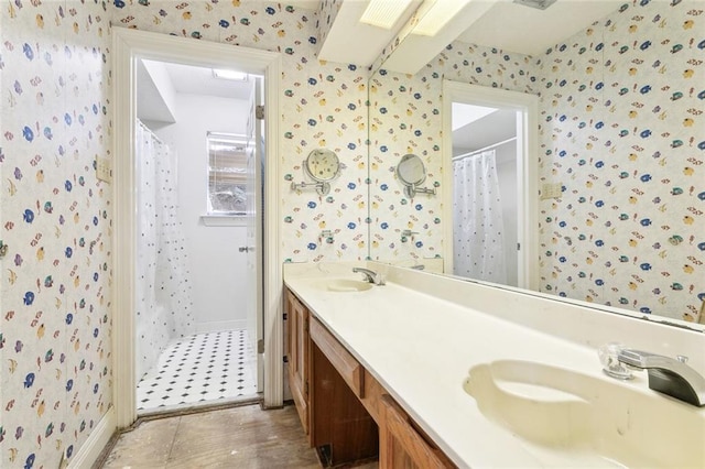 full bath with a shower with shower curtain, double vanity, wallpapered walls, and a sink