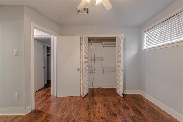 unfurnished bedroom with visible vents, a closet, wood finished floors, baseboards, and ceiling fan