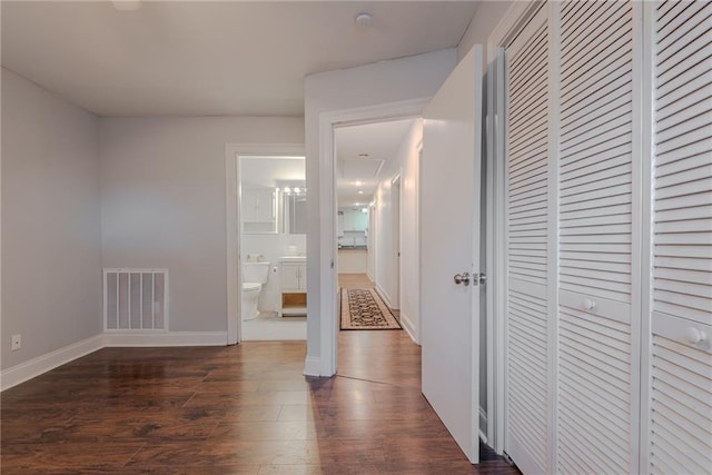 unfurnished bedroom with baseboards, visible vents, dark wood finished floors, and a closet