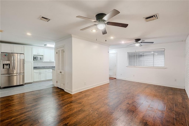 unfurnished living room with visible vents, a ceiling fan, baseboards, and wood finished floors