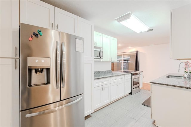 kitchen featuring appliances with stainless steel finishes, light stone countertops, a sink, white cabinets, and light tile patterned flooring