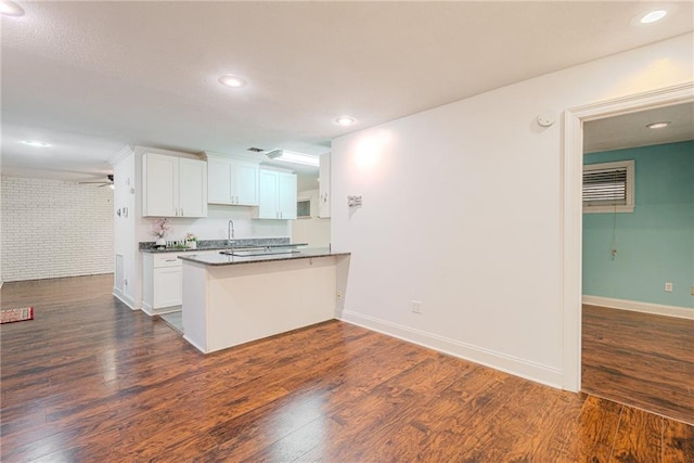 kitchen with dark wood-style flooring, white cabinetry, a peninsula, and dark countertops