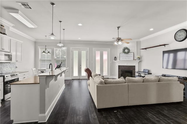 living area with crown molding, a fireplace, recessed lighting, a ceiling fan, and dark wood finished floors