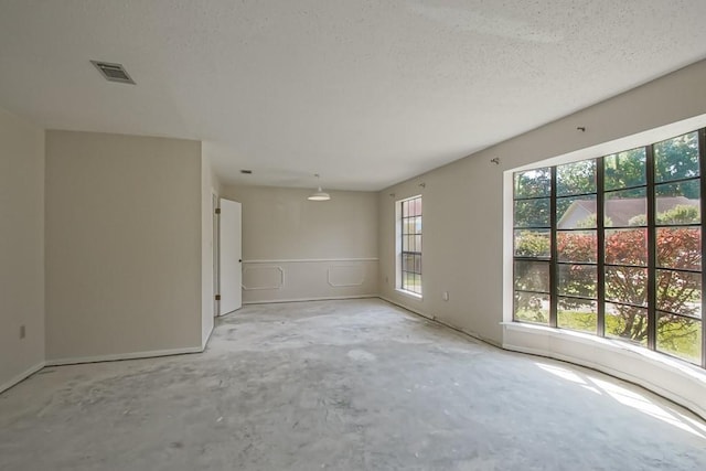 empty room featuring a textured ceiling, visible vents, and unfinished concrete floors