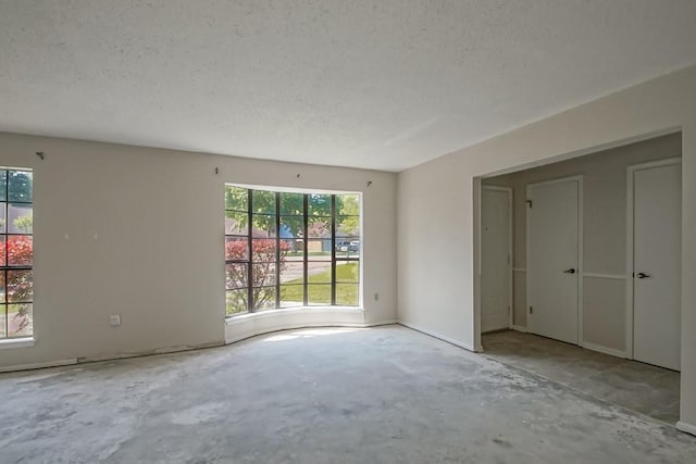 interior space featuring a textured ceiling, plenty of natural light, and unfinished concrete floors