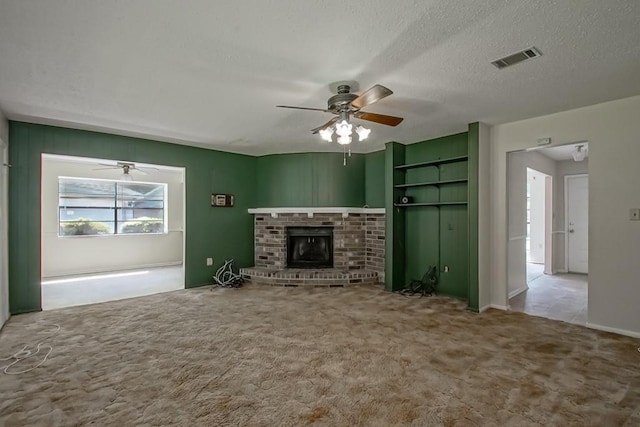 unfurnished living room featuring visible vents, a brick fireplace, ceiling fan, a textured ceiling, and carpet flooring