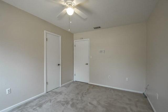 carpeted empty room with baseboards, a ceiling fan, and visible vents