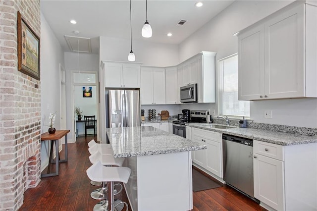 2430 Clara St, New Orleans, LA 70113 - kitchen featuring appliances with stainless steel finishes, white cabinets, a center island, a kitchen breakfast bar, and recessed lighting